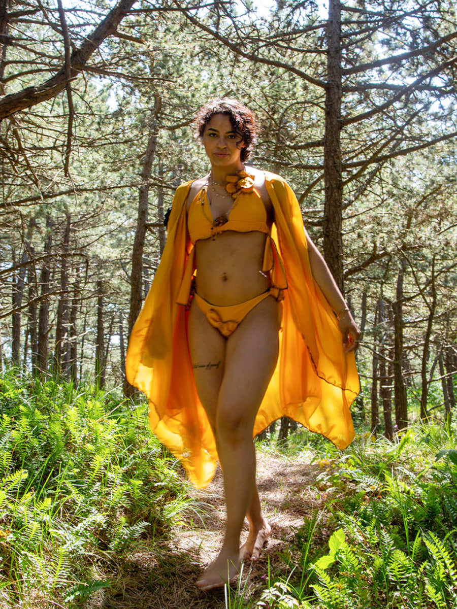 Woman in sunlit woods wearing orange Cavalcante bikini and wrap