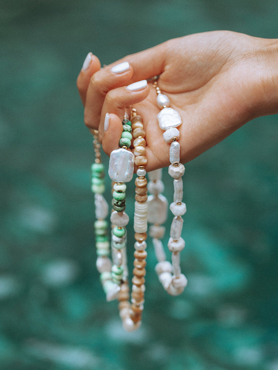 Womans hand holding Keilani necklaces made of semi precious stones