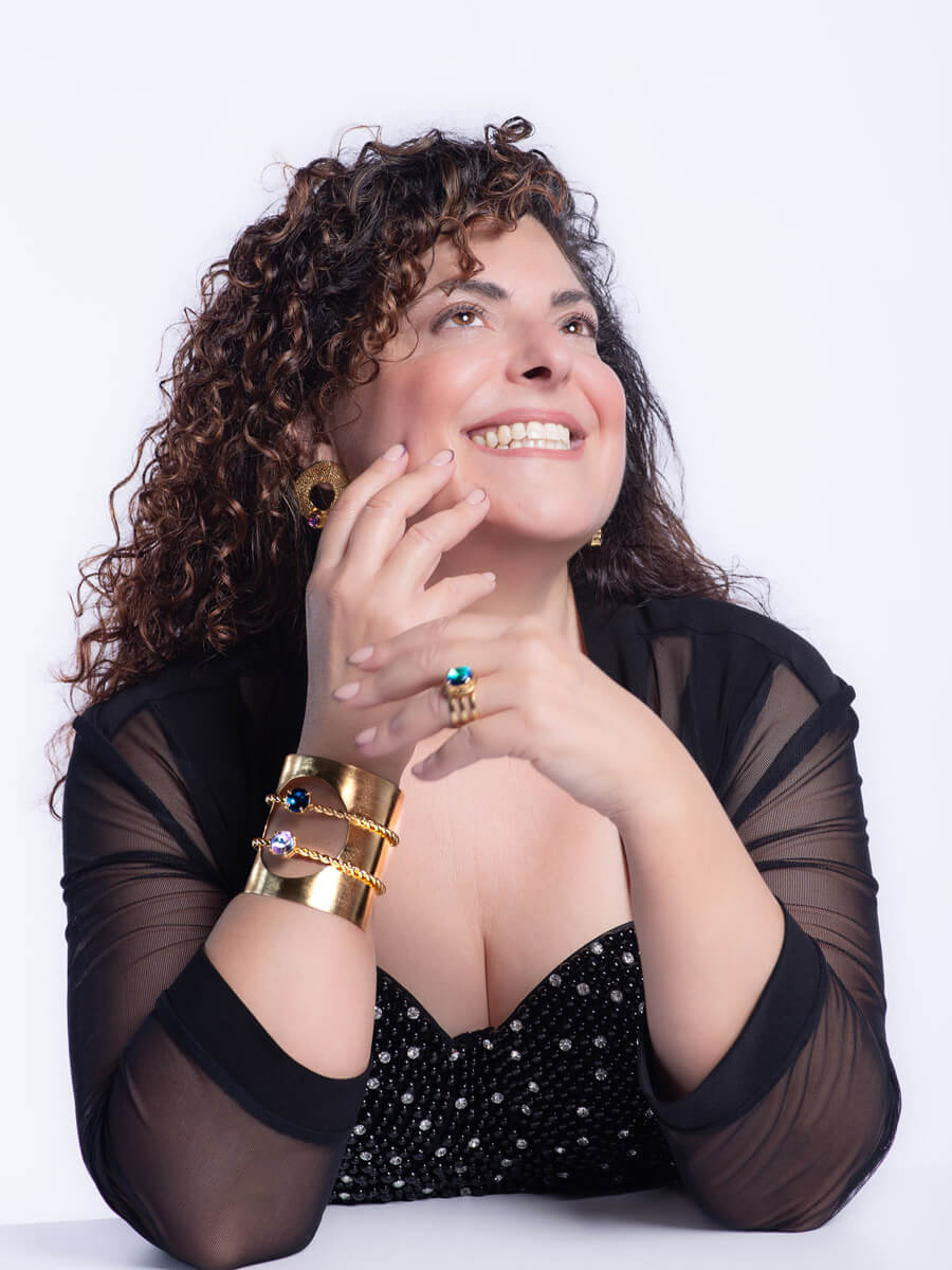 Woman looking up smiling wearing black with elbows on table in white room